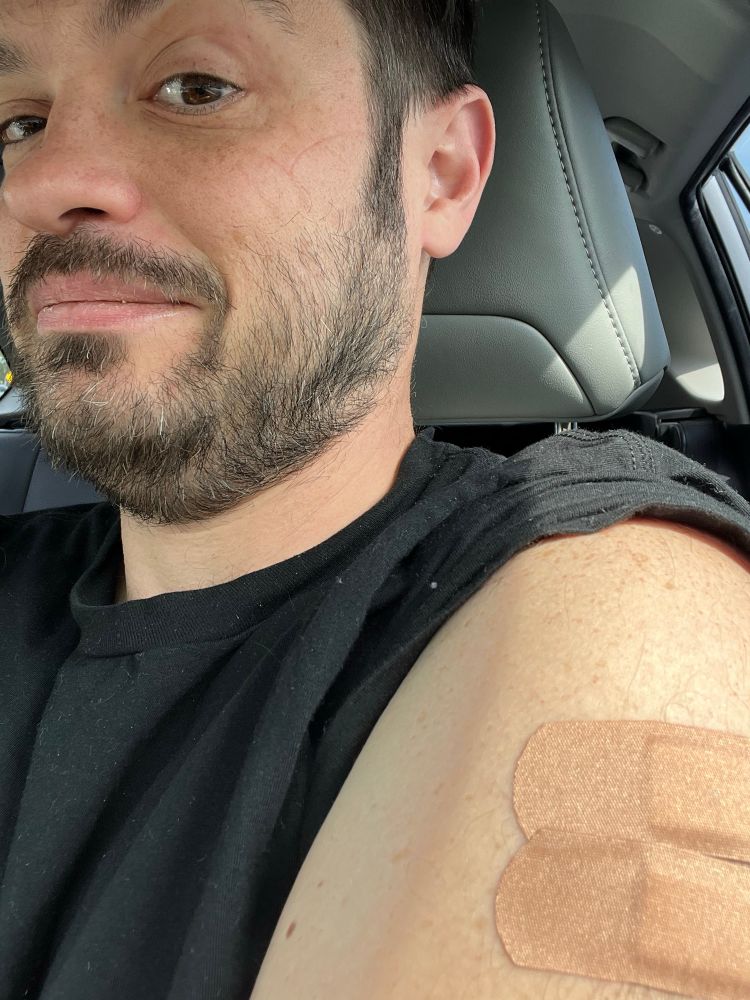 A man in a black t shirt with two bandaids