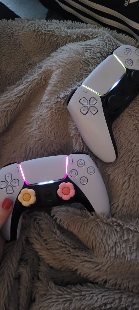Two playstation controllers indicating the player lights. One has pink lights and one has green light