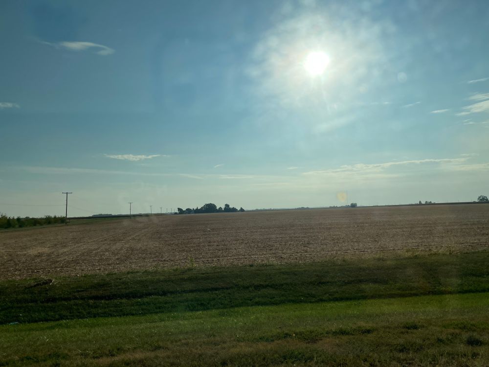 Through a slight haze, the am sun shines down on a newly harvested field. The straw remaining is evidence that this was a crop of soybeans. 