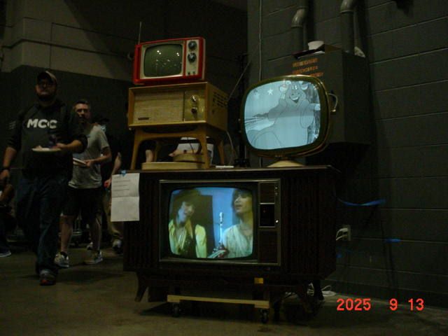 three vintage TVs and a vintage radio. two are powered on: a b&w philco predicta and a 1968 zenith color space command.