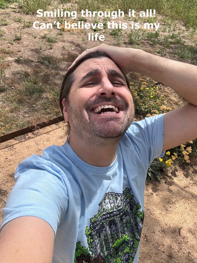 Michael wearing a light blue t-shirt emblazoned with an image of the Supreme Court building, ruined and decayed and overtaken by nature. Green plants grow over and through it. Michael has one hand on his head and a ridiculous open mouth grin, looking up at the sky with his eyes squinted, in the same pose as an infamous Lebron James selfie. The caption is the same as the Lebron one: "Smiling through it all! Can't believe this is my life" 