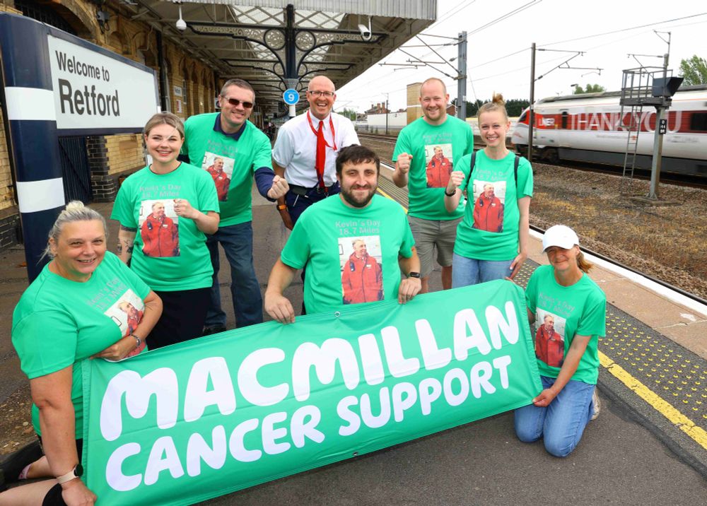 The Retford station team and Kevin’s family holding a MacMillan Cancer Support sign, with the Azuma ‘Thank You’ passing on  the Up Fast