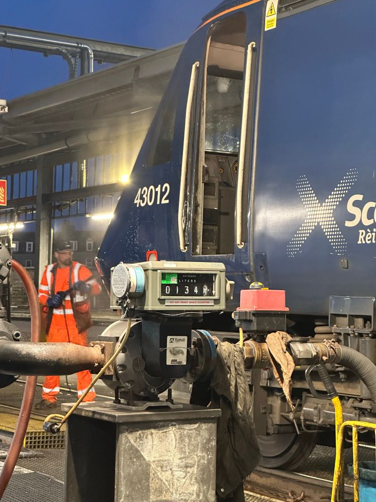 The front of HST power car 43012 being cleaned by a member of the LNER team using a pressure washer at the fuel point at Clayhills, the fuel gauge reads 1339 litres