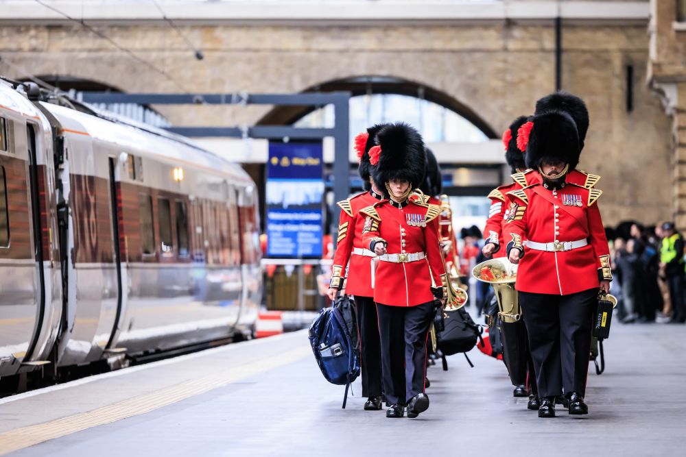 The Coldstream Guards in their red tunics and bearskins marching along platform 8 at King’s Cross station alongside Azuma train 800111 named “Thank You”