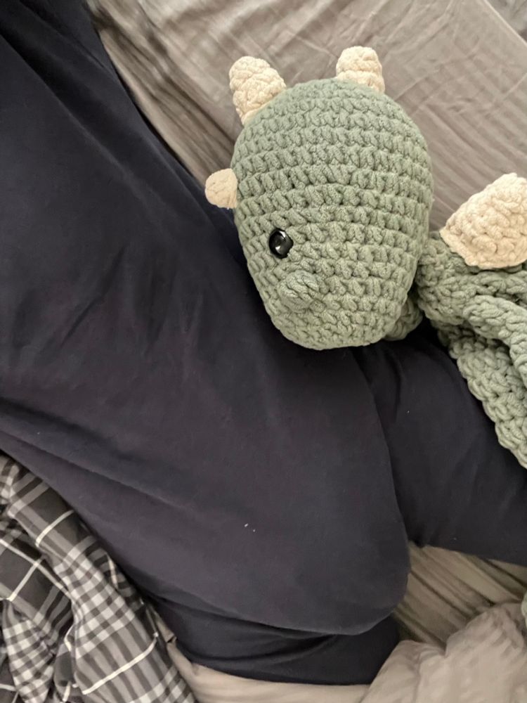 An extra obvious Diane bulge beneath my Little Keeper Sleepers. My green crocheted dinosaur name Mercutio lays next to me with his oversized head facing my diapered bottom. 