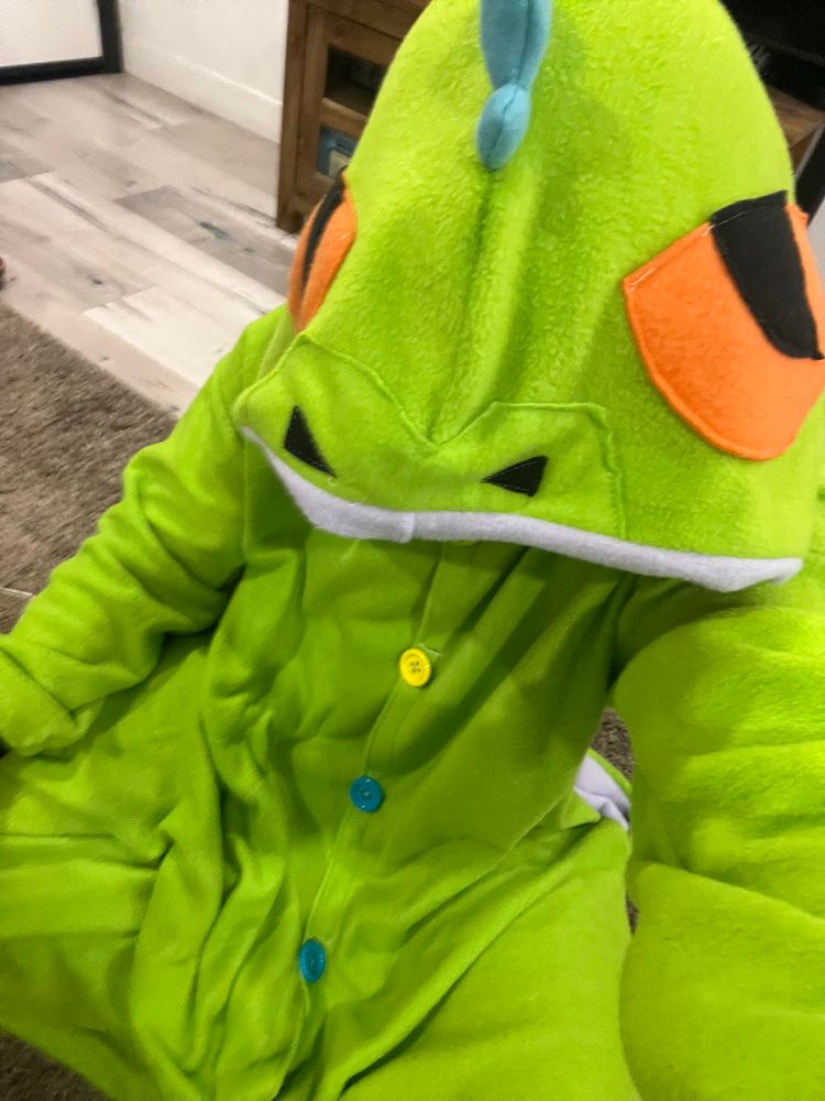 Me wearing my green Reptar kigu with new, larger, and more colorful button. My head is obscured by the oversized hood. 