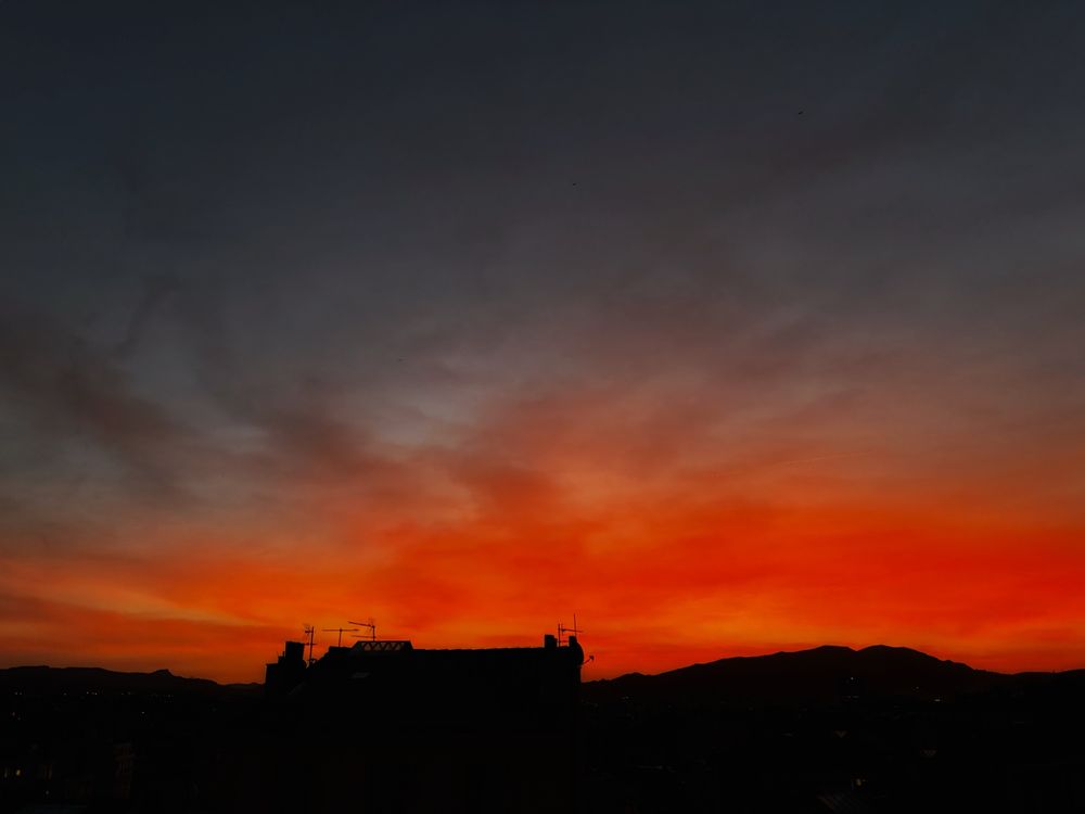 My early morning sunrise view from Marseille!

A vivid orange sky dominates the horizon. Fine grey grey clouds complete the sky view.

The distant horizon and city buildings add darkness to the landscape.