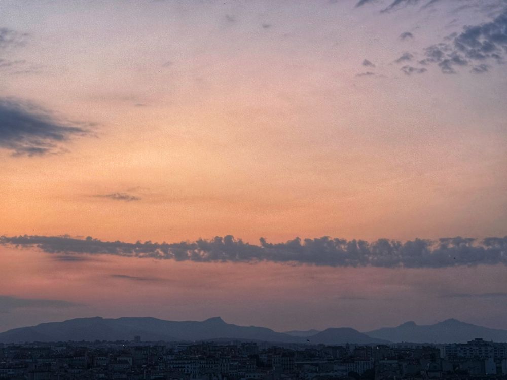 Sunrise view over Marseille. A closer view of the various colours in the sky overhead. The orange glow provides a greater contrast to the distant mountains.