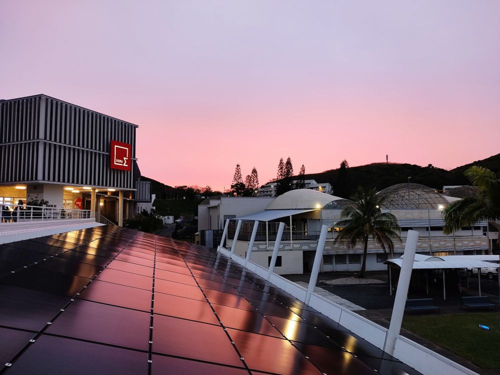 Coucher de soleil sur l'université de Nouvelle Calédonie, le ciel est rose et se reflète sur les bâtiments