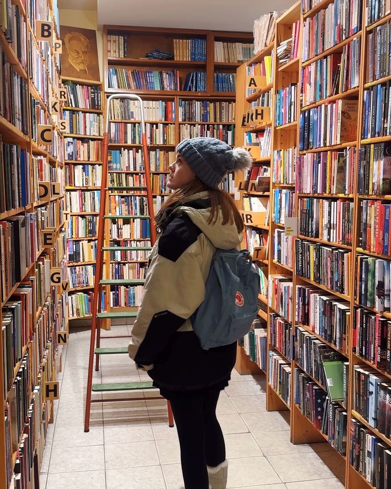 Me standing in a bookshop looking up at the shelves of books