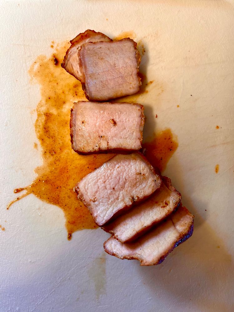 A sliced up pork chop on a cutting board in this image. 