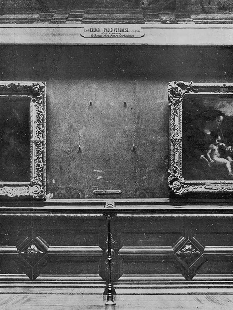 A black and white photo of an empty space between two paintings on a museum wall.