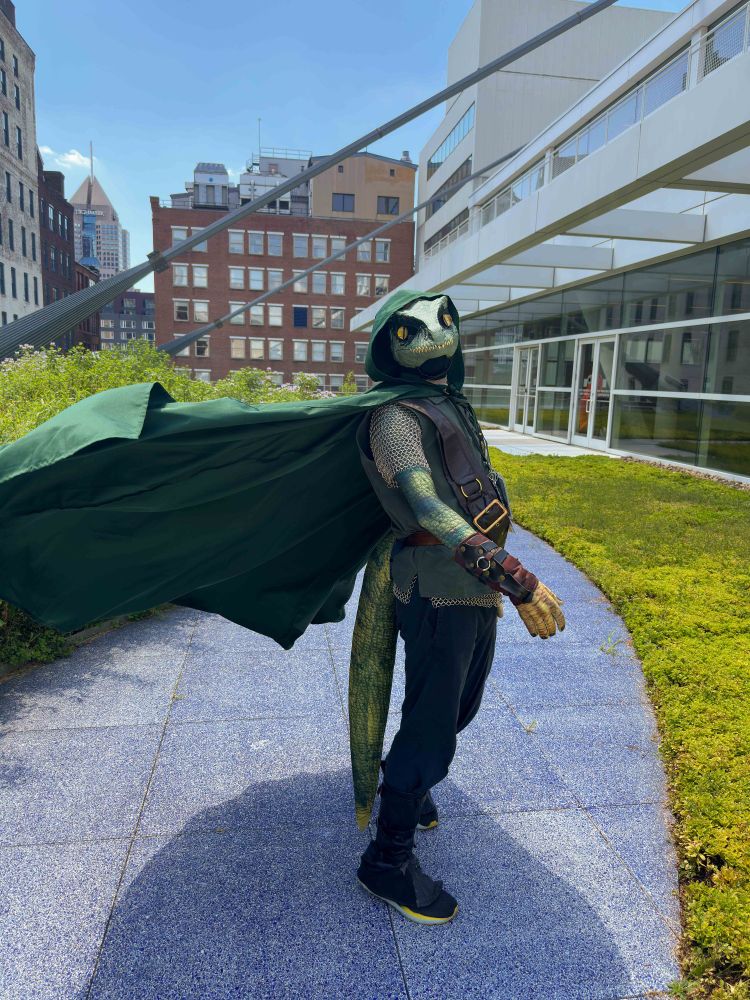 Person in green scaly character outfit with billowing green cape