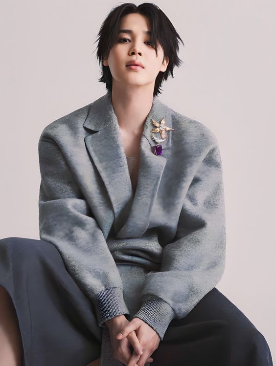 Park Jimin for Harpers Bazaar. Jimin wears dark gray pants and a lighter gray suit/sweater that is slightly oversized. He is looking directly at the camera because he doesn't actually care about whether or not our hearts explode with the eye contact.