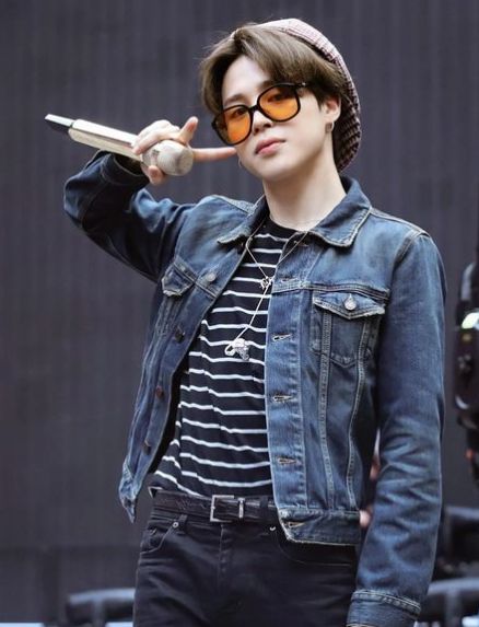 Cutie, sexy, lovely Jimin in dark jeans, a dark striped shirt and denim jacket. He's holding his microphone in one hand and making a peace sign by his face.