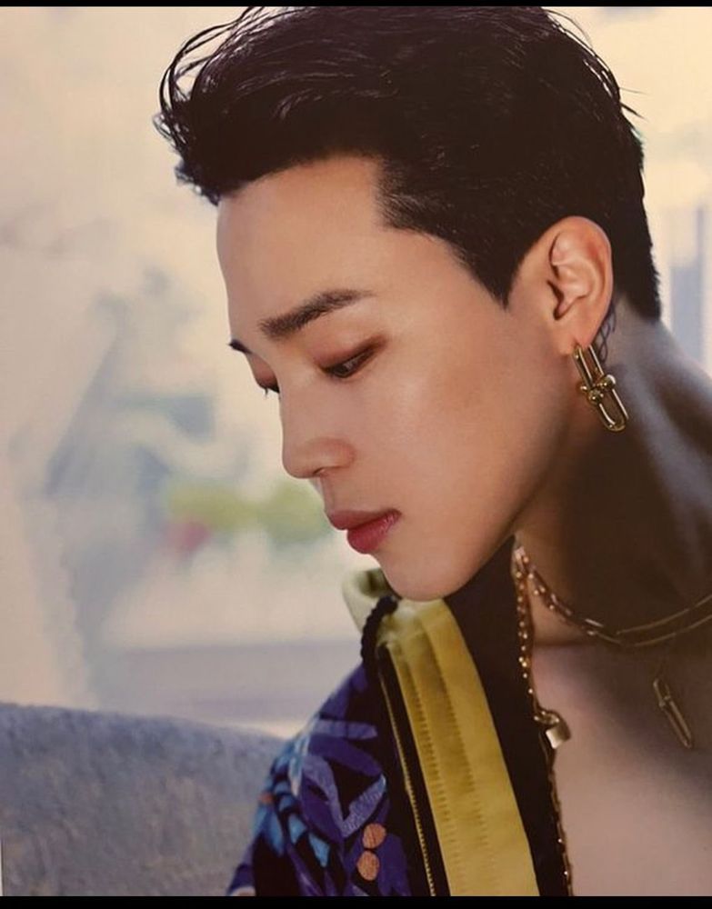 Jimin's profile as he looks down and to the left. Gold earring, gold chains around his neck and an open jacket offering just a tantalizing glimpse of his naked chest...