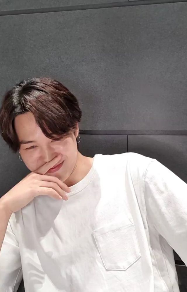 Screenshot from a past Jimin live. He is wearing a white tshirt and smirking seductively with a finger over his mouth.