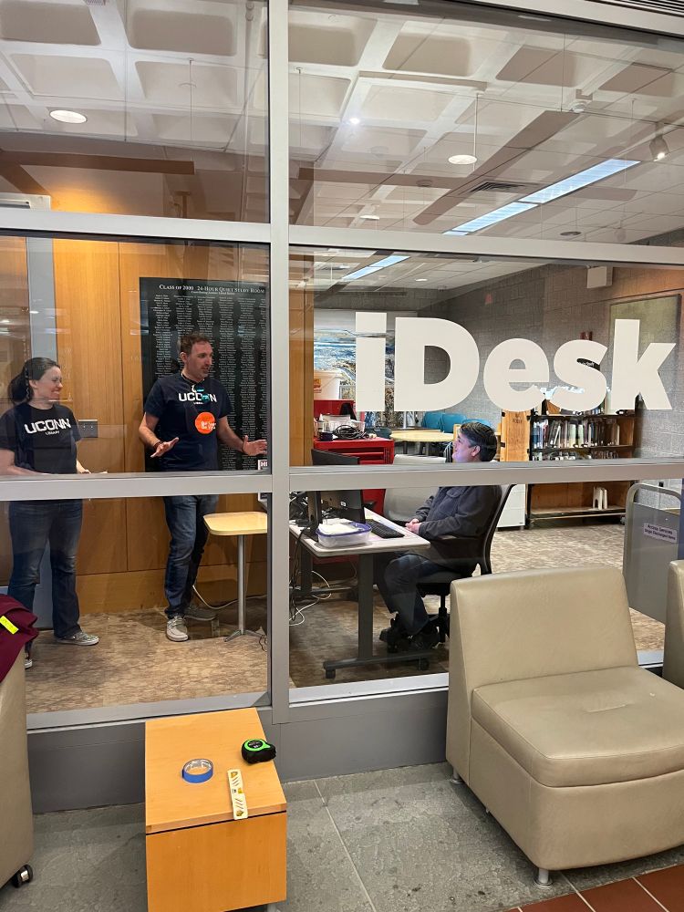 Two people standing at the iDesk