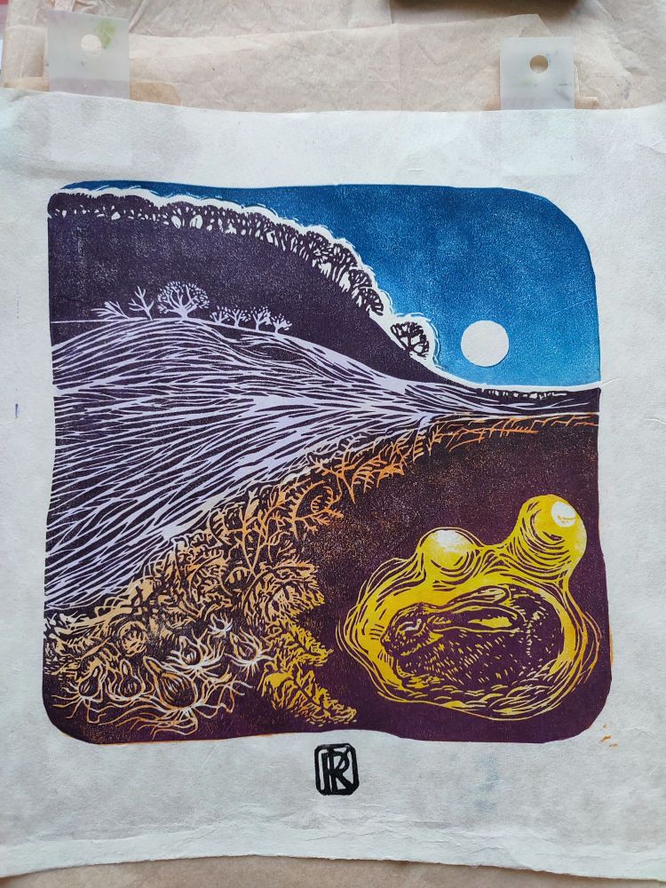 A lino print of a rabbit in its burrow near bulbs and bracken in warm oranges and browns as a full moon rises over a wind ravaged valley in cool purples