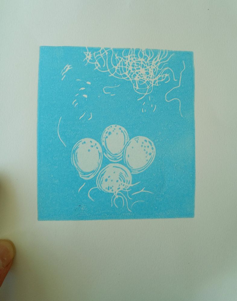 A print of the second layer of a reduction of eggs in a nest in light blues. 4 eggs nestle and some of the white wool used to weave the best is visible.