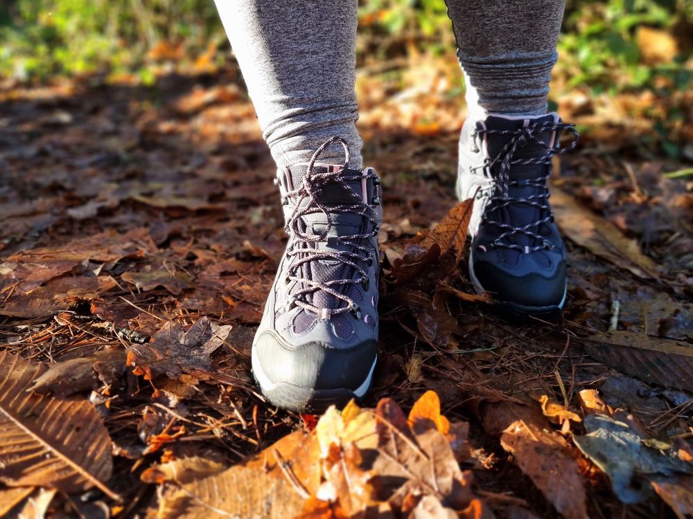 Boots on a path covered in leaves, golden sun shining 
