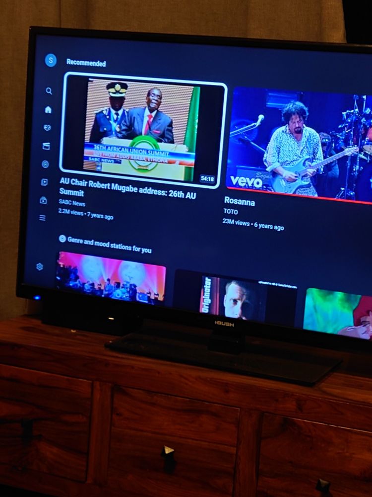 A picture of a TV displaying YouTube recommendations, the selected one being AU Chair Robert Mugabe: 26th AU Summit, the next one being 'Rosanna' by Toto