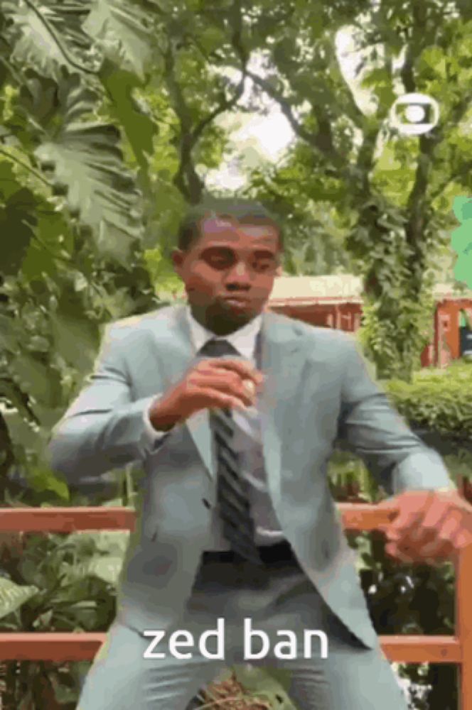 a man in a suit and tie is standing in front of a wooden fence and trees .