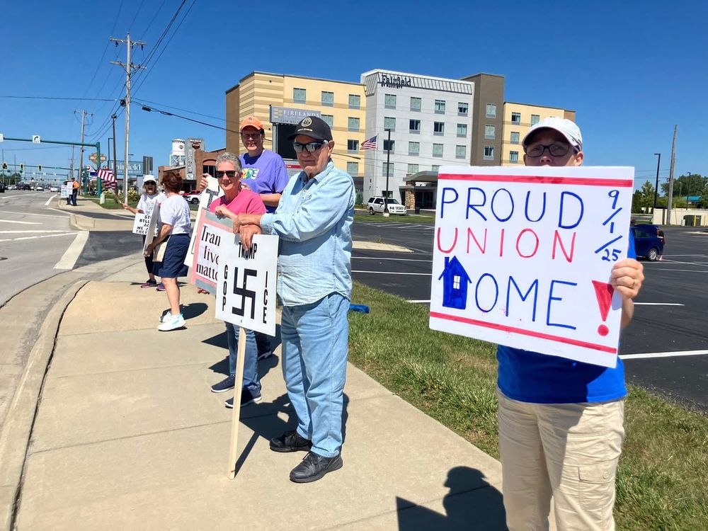 People holding protest signs. Says, Proud Union Home.