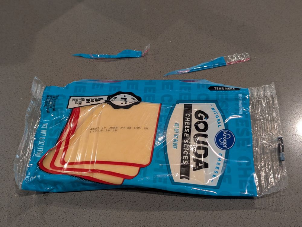 A package of cheese slices with both sides of the tearable edges broken off without opening the package