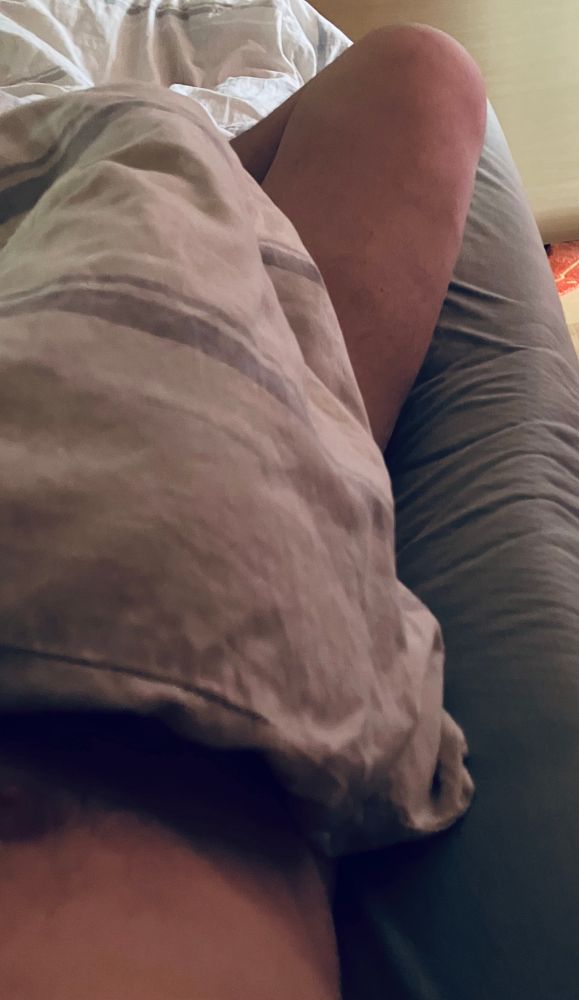 dunkelgraue Matratze, hellgraue Bettdecke, Teil von Pims nacktem Bein & nackter Brust.