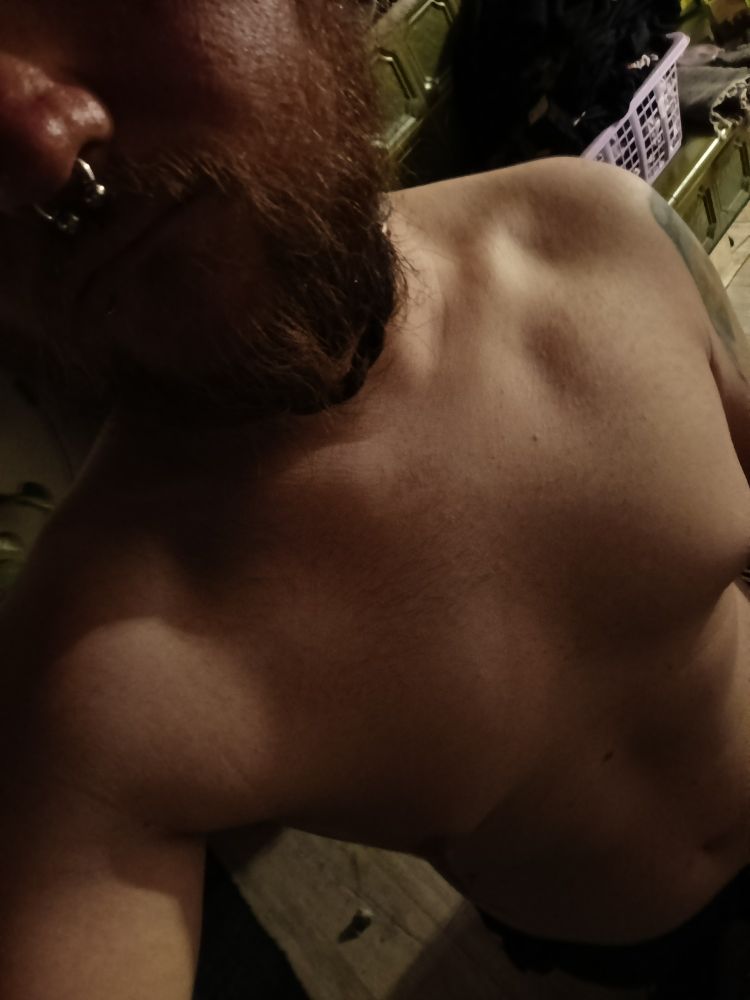 Oberkörperfreies Foto einer manmochen Person mit Bart und Septum 