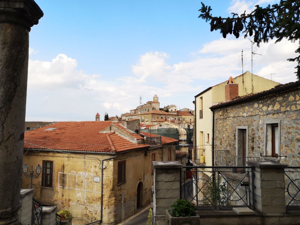 de la place Umberto 1er, entre les maisons de pierres grises parfois enduite de jaune, on voit s'élever le village avec, en son point le plus haut la tour de l'horloge . 