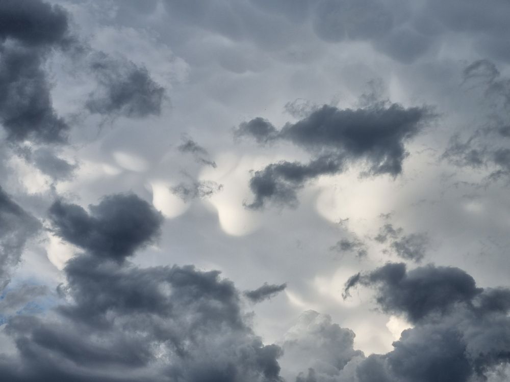 A photo of grey clouds, some of which appear to almost be melting in great blobs, as if made from pale-grey gel.