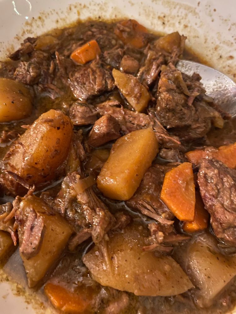 Image of a bowl of stew, with chunks of beef, potatoes, and carrots in a thick broth