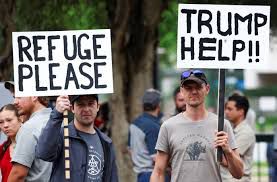 Two white South Africans plead for Trump’s help. Their signs read: 1) REFUGE PLEASE; 2) TRUMP HELP!!