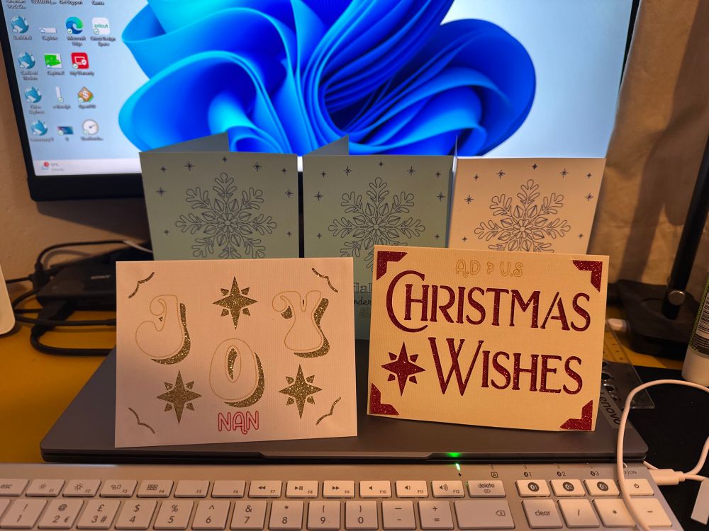 Christmas cards three of a same design with blue glitter gel and two of a different design one with joy in gold and Christmas wishes in red 