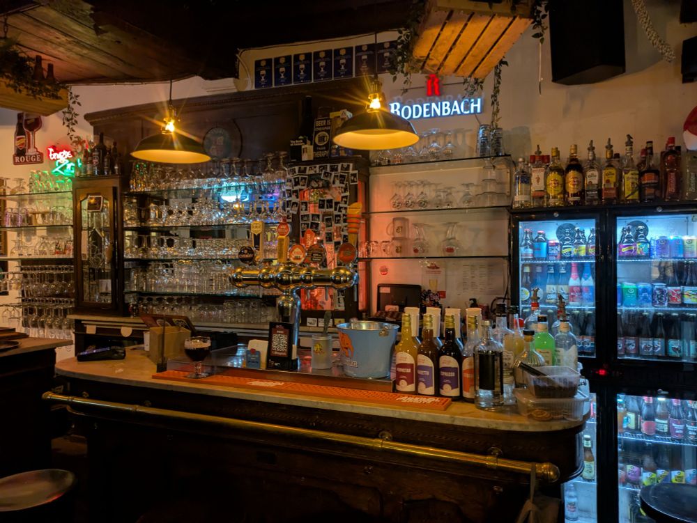 A view of cafe 't Waagstuk bar with glasses behind it and overhead lighting 