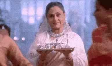 a woman in a white dress is holding a tray of tea cups in her hands .