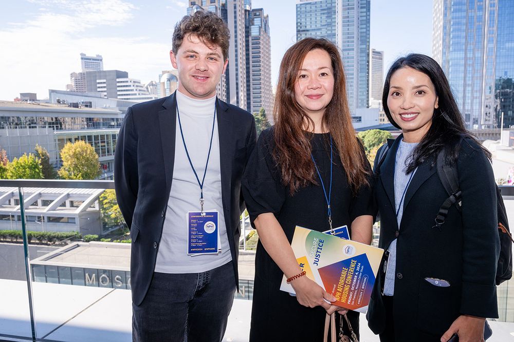 Three conference attendees on an outdoor patio with Conference materials in hand.