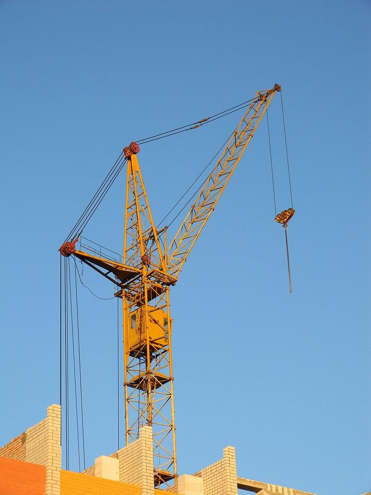 Top of crane against a blue sky in the middle of a new structure.