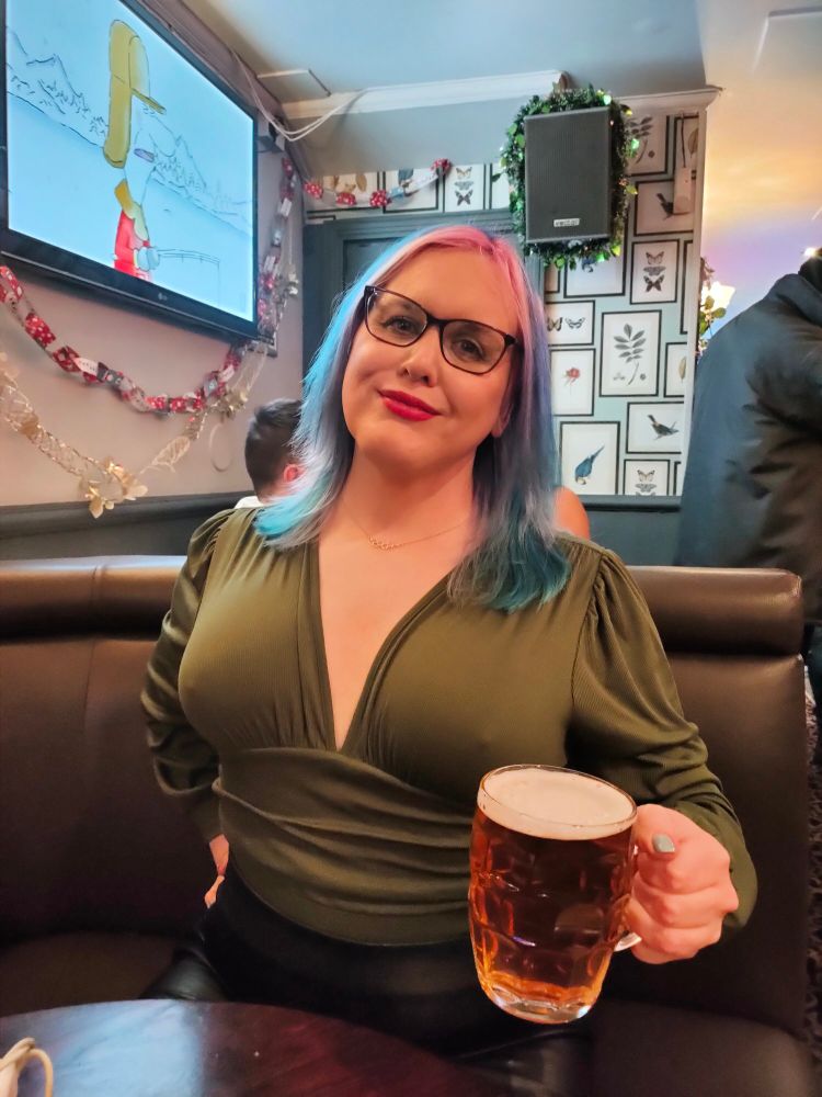 Sitting in a booth holding a dimple mug glass of cask ale. 

