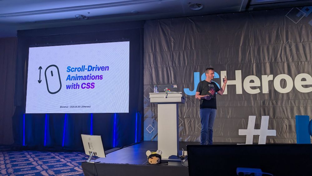 Bramus entering JS Heroes stage with his title slide in the background 