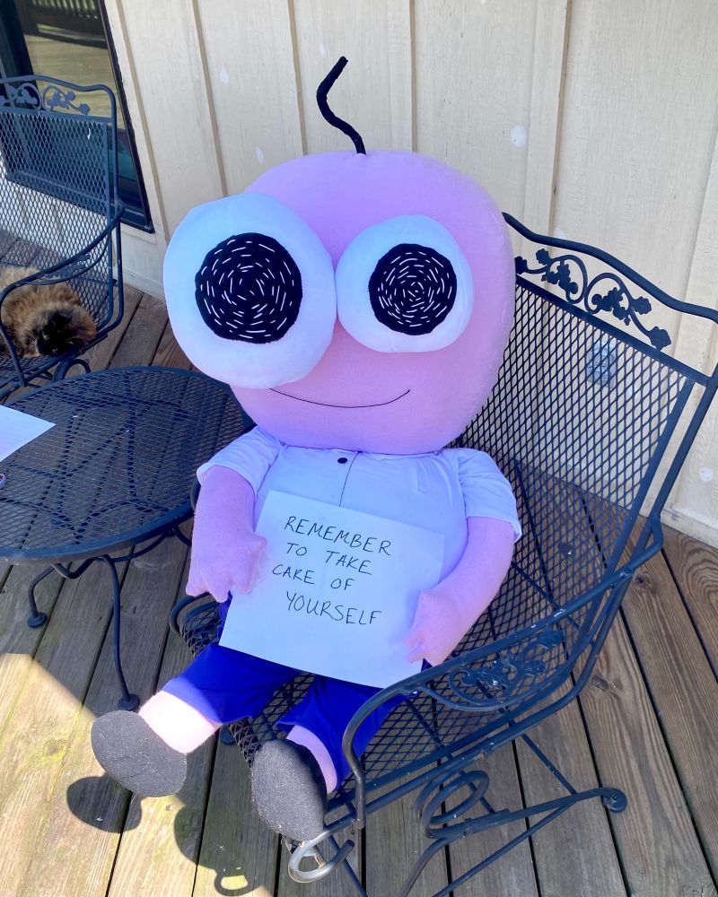 pim from smiling friends smiling and holding a sign that says “remember to take care of yourself”