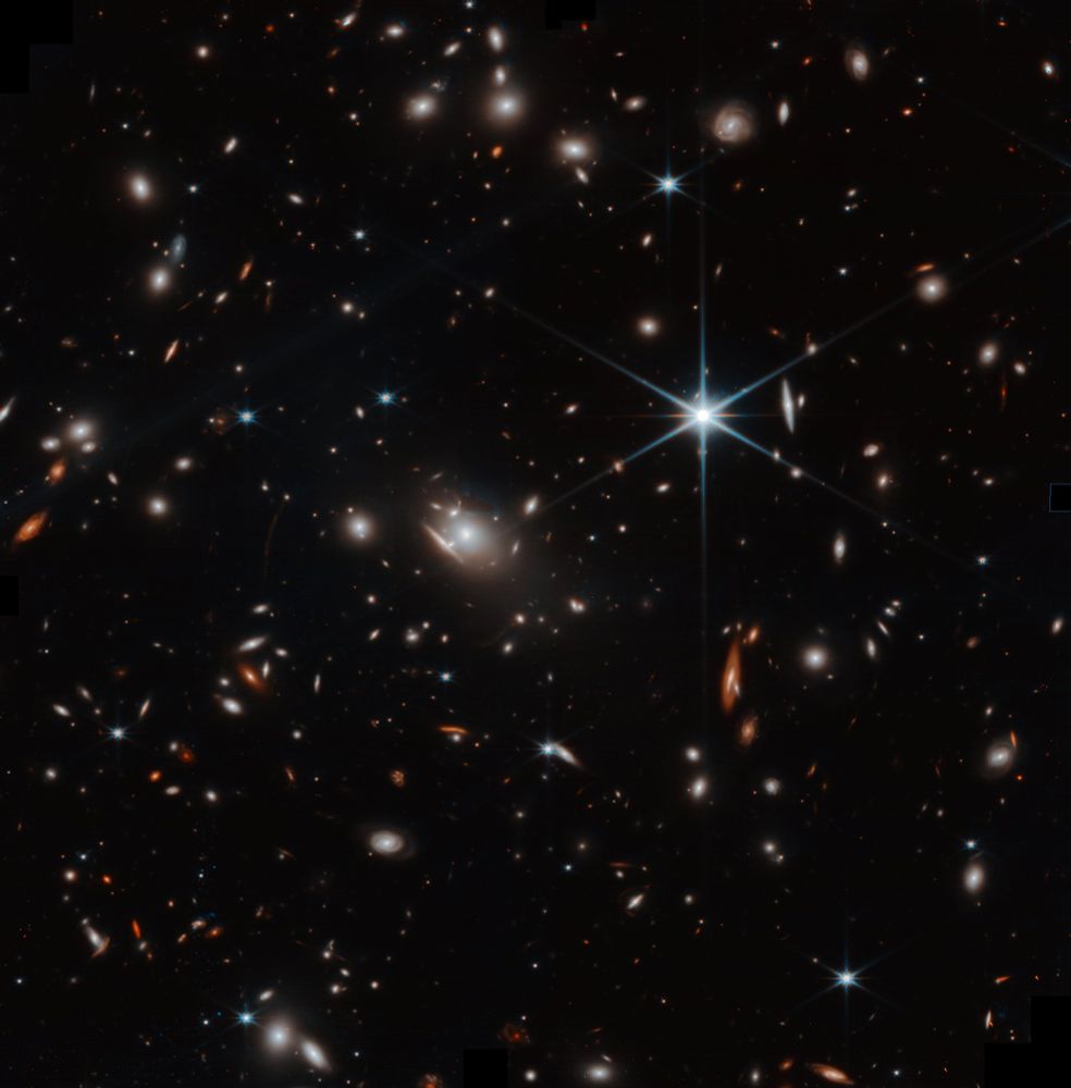 The image, taken by the NIRCam instrument on the James Webb Space Telescope, shows a cluster of galaxies called PSZ2G046.10+27.18. The cluster is located about 4.6 billion light-years away from Earth. In the center of the image, a bright, distorted galaxy is visible. This is a result of gravitational lensing, which occurs when the mass of a massive object, such as a galaxy cluster, bends the light of objects behind it. This creates multiple images of the same object, which can be seen as distorted arcs and streaks of light around the central galaxy. The image also shows many other galaxies, both bright and faint, scattered throughout the field of view. These galaxies are members of the cluster, as well as galaxies that are located behind the cluster but are not being lensed.