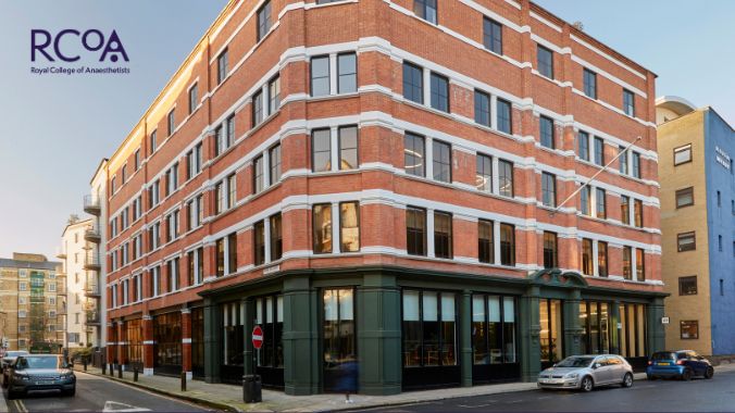 Photograph of Jubilee House, a seven-storey building (five of them visible in the photograph) in red brick with a ground floor facade painted dark green. 