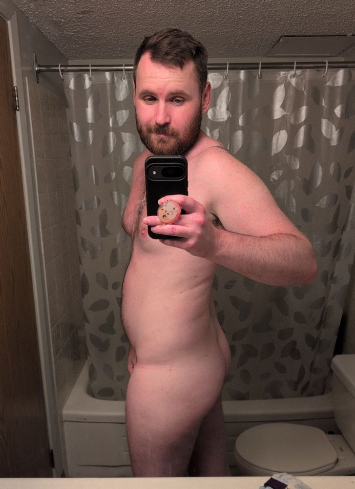 A bathroom mirror selfie of myself at a side profile. My phone has a Patamon pop socket and I am not wearing clothes.