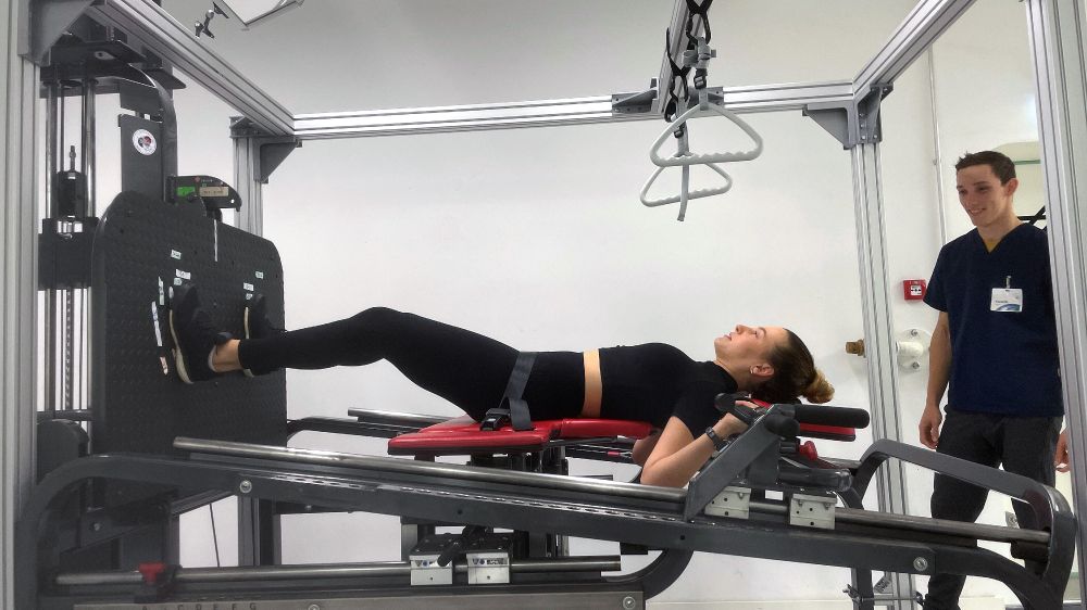A study participant performing strength training on equipment, while lying down.