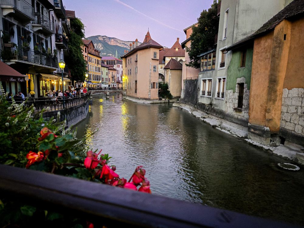 The Palais de l'Ile, a fortress that has been around since the middle ages, built on a small rocky island in the Thiou River, Annecy, France. The river cuts through the city in a series of canals, so people often call it the Venice of the Alps. In the background are the French Alps. 