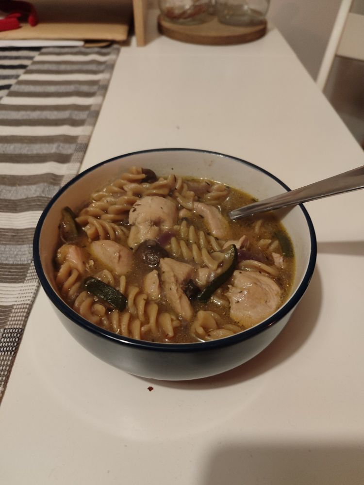A bowl of chicken noodle soup with veggies
