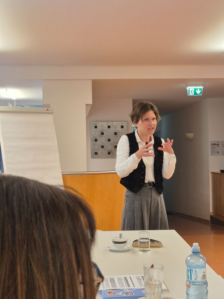A woman with short brown hair and white skin gesturing as she speaks. 